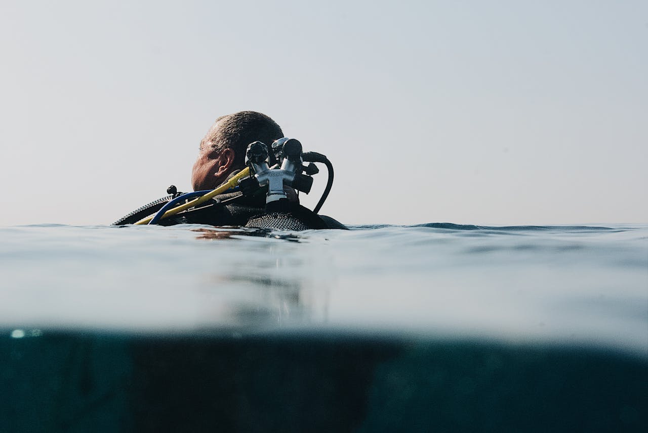 gallery-03 A scuba diver floats at the water's surface in an over-under shot, capturing ocean exploration.
