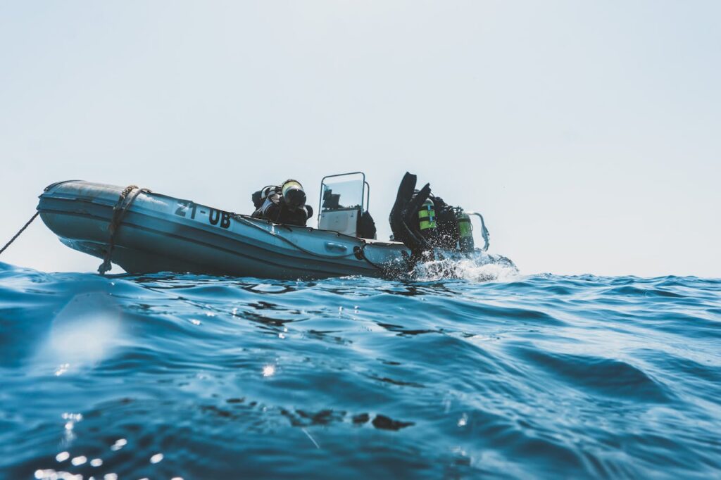 pexels-photo-3113238 Scuba divers equipped for an ocean dive prepare from an inflatable boat on a sunny day.